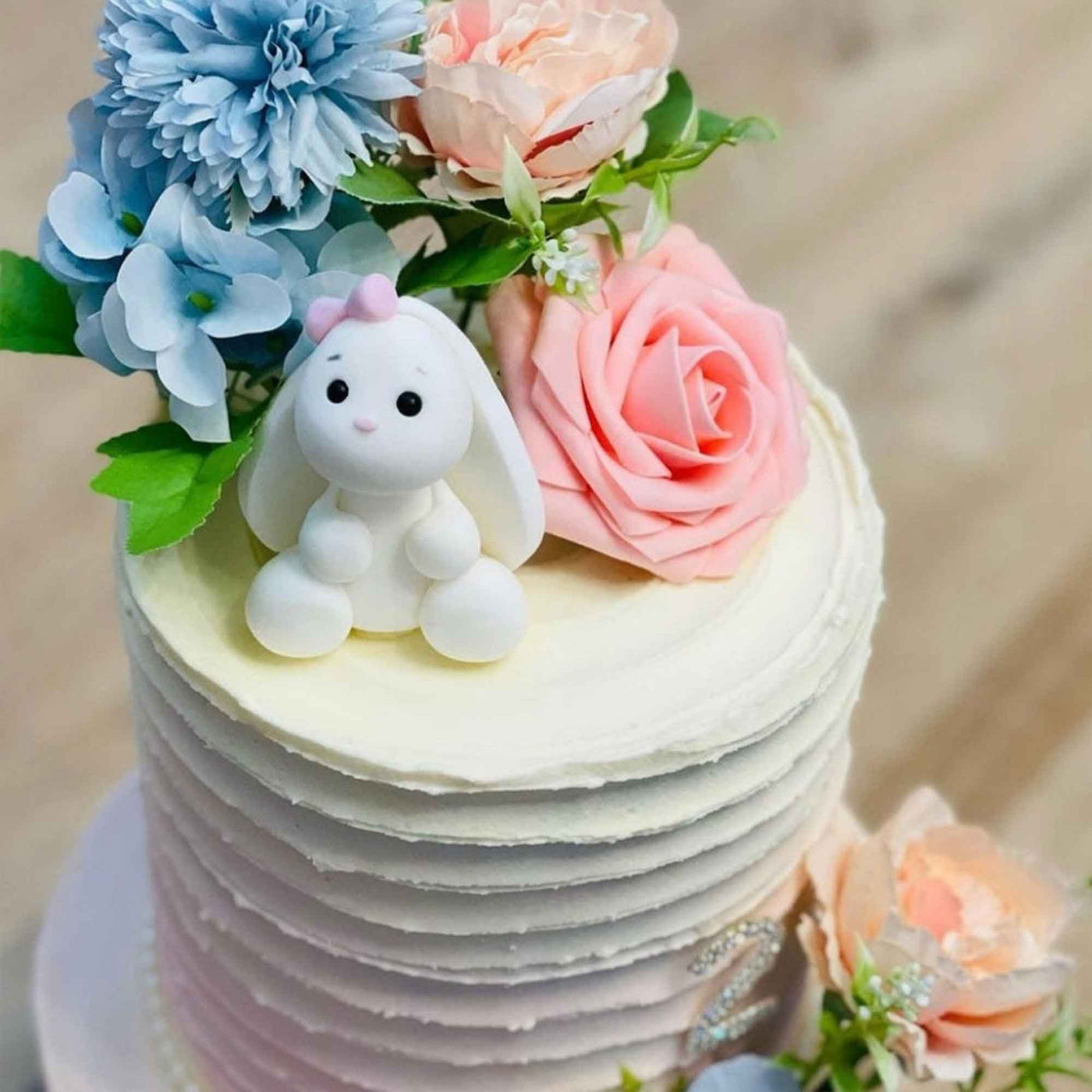 Kanin i sockerpasta med rosett på en tårta dekorerar med blommor
