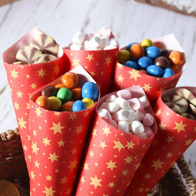 Godisstrutar gjorda av julrött karamellpapper med gyllene stjärnor fyllda med färgglatt godis och marshmallows.