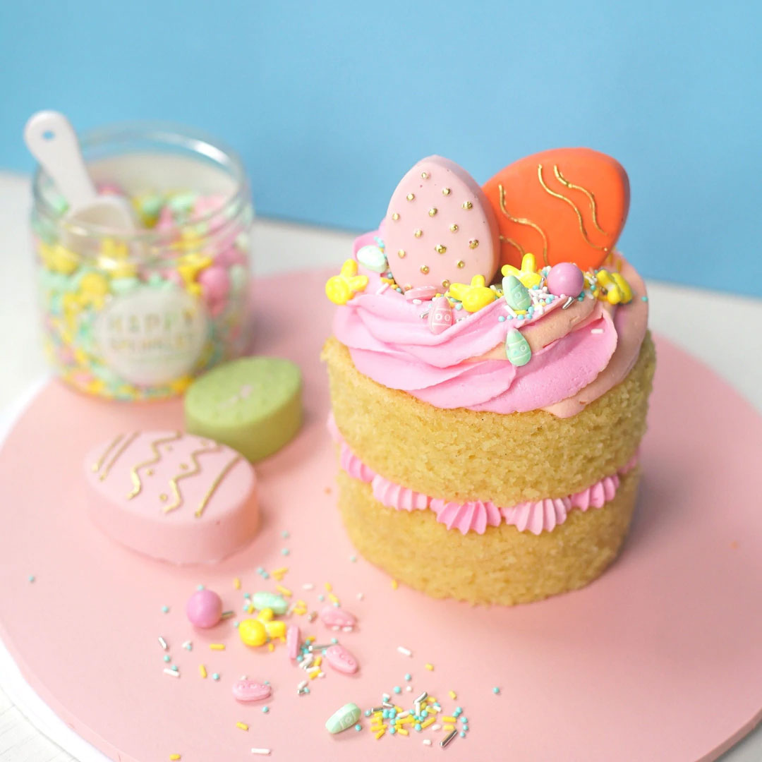 Liten tårta dekorerad med rosa glasyr, färgglatt strössel och chokladägg gjorda med silikonform.