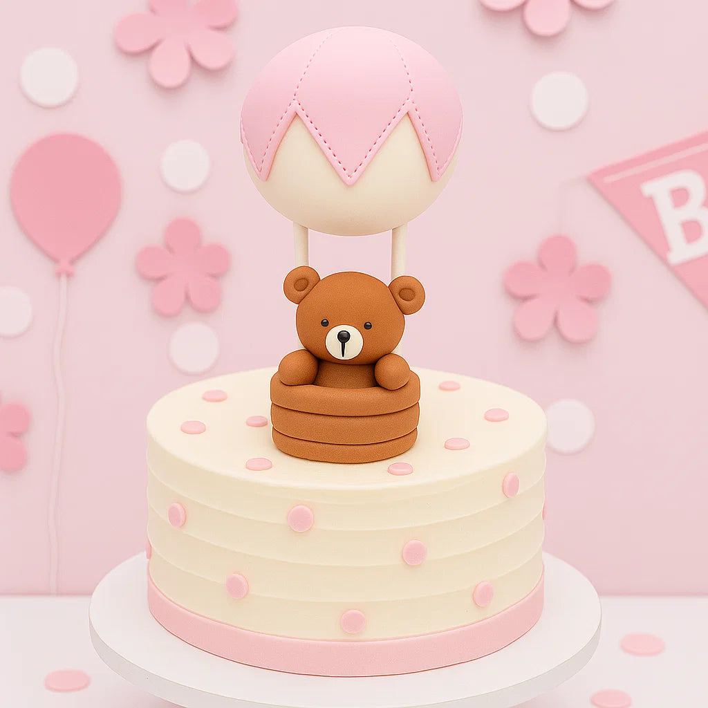 Nalle med rosa luftballong som pryder en rosa tårta till baby shower för en flicka