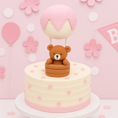 Nalle med rosa luftballong som pryder en rosa tårta till baby shower för en flicka