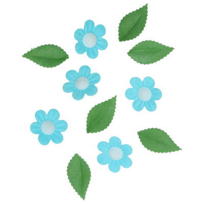 Blå ätbara waferblommor och gröna blad från Wilton utspridda mot vit bakgrund