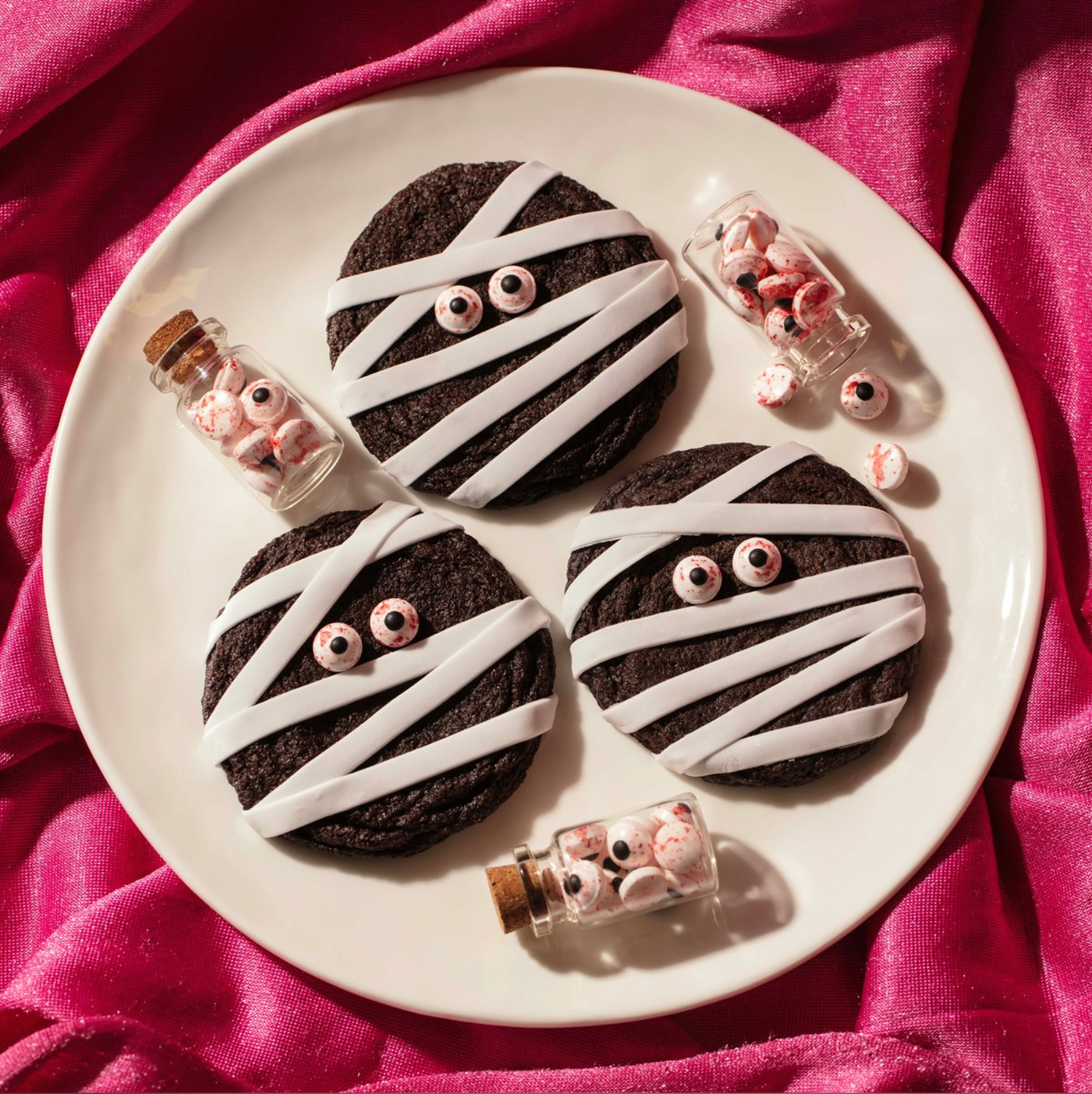 Chokladkakor med vit glasyr och PME Bloody Eyes serverade på tallrik med små glasflaskor fyllda med ögon