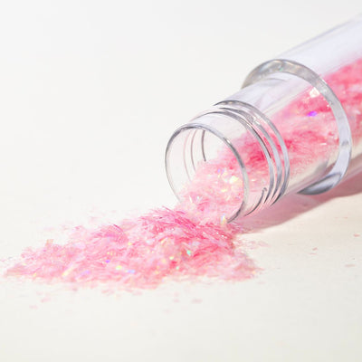 Öppen burk med rosa ätbara glitterflakes från PME som rinner ut på vit yta