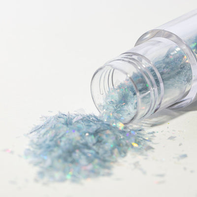 Ströburk med silverglitter som hälls ut på vit bakgrund