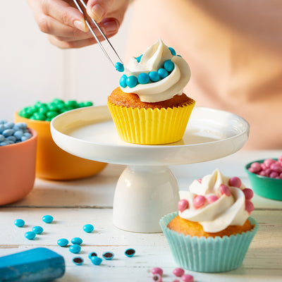 Färgglada chokladpärlor som topping på cupcake med vit frosting