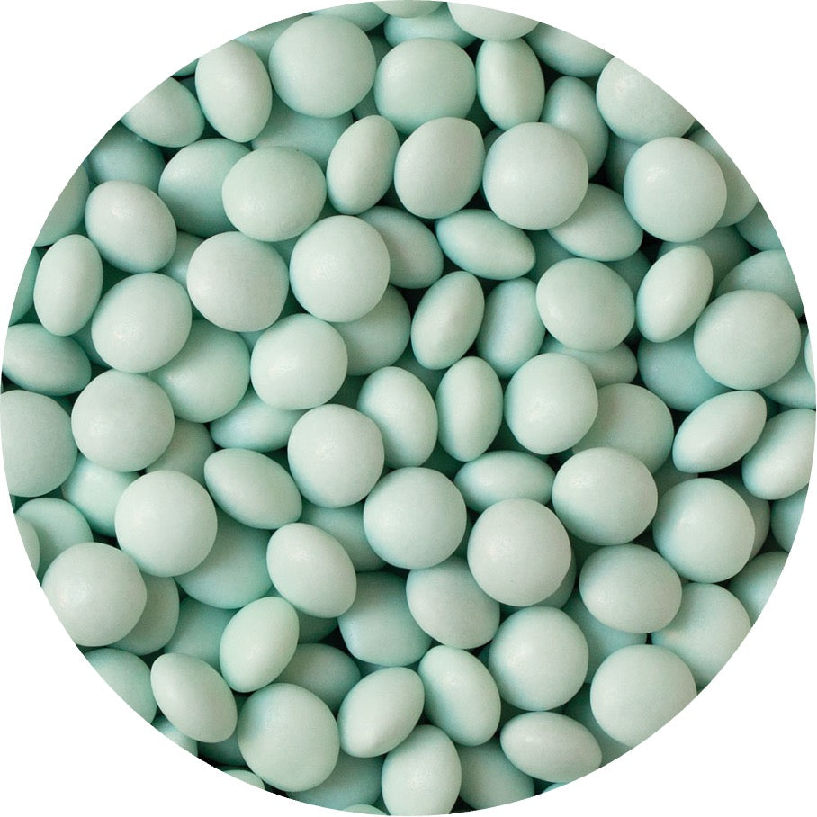 Närbild på pastellgröna chokladpärlor från Decora med blank yta, idealiska som ätbart strössel till bakverk.