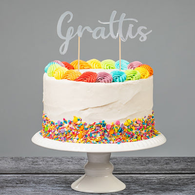 Cake topper i silver med texten Grattis som sitter i en födelsedagstårta