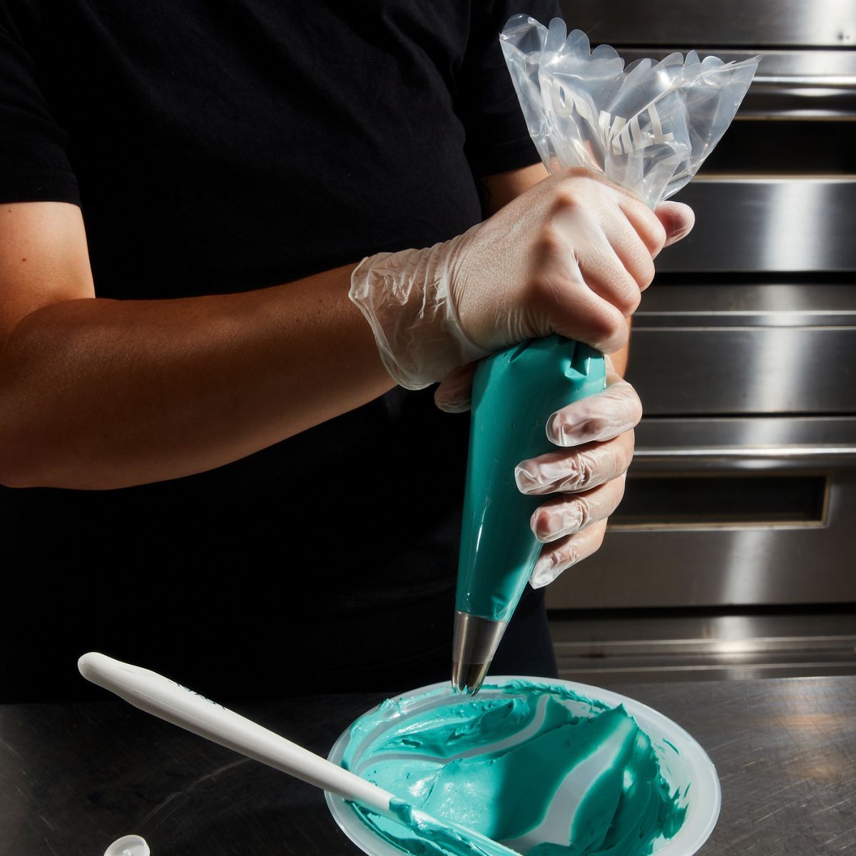 Person spritsar turkos frosting med engångsspritspåse från Colour Mill