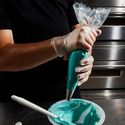 Person spritsar turkos frosting med engångsspritspåse från Colour Mill