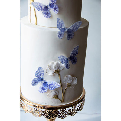 En vit tårta med lila, ätbara fjärilar som dekoration