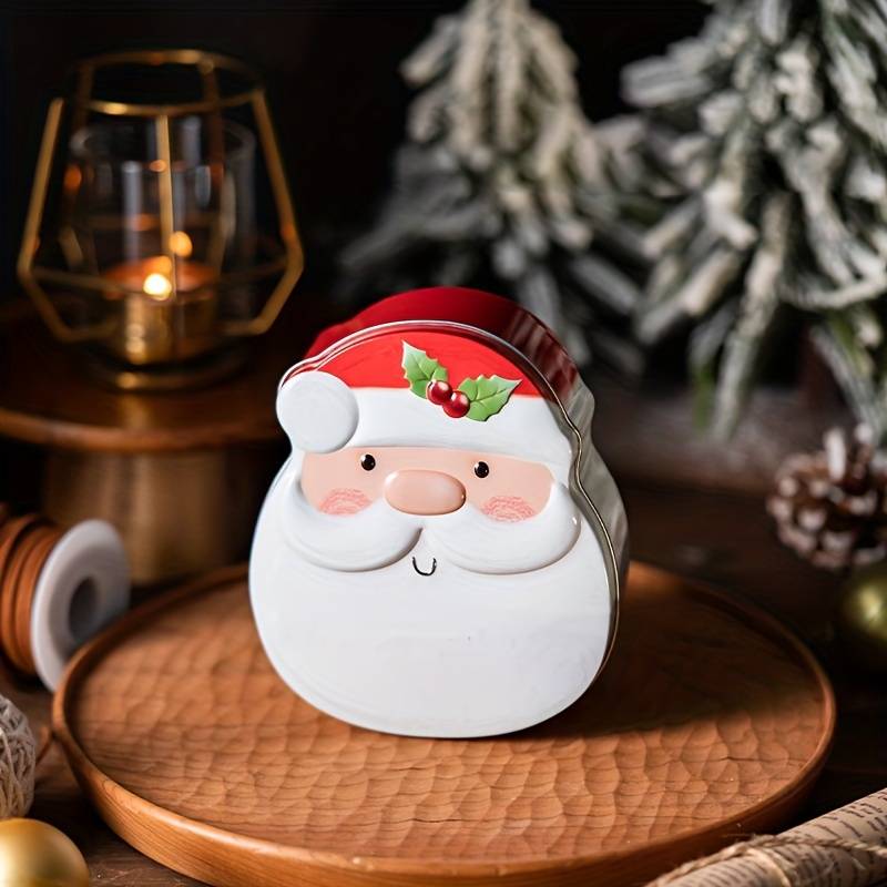 Plåtburk formad som en tomte med röd mössa och vitt skägg placerad i julmiljö på ett träfat