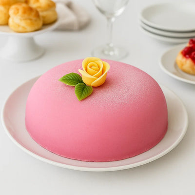 Tårta täckt med rosa marsipan dekorerad med gul ros i marsipan