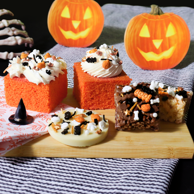 Olika bakverk dekorerade med Halloweenströssel i svart, orange och vitt