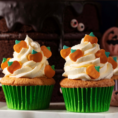Två cupcakes med vit frosting toppade med PME Halloween-pumpa-strössel