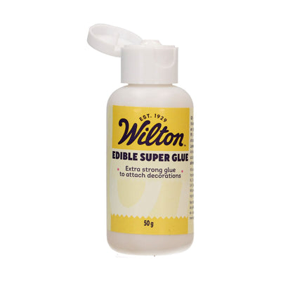 Wilton Edible Super Glue 50 g med gul etikett och öppet lock – starkt och snabbtorkande lim för tårtdekor.