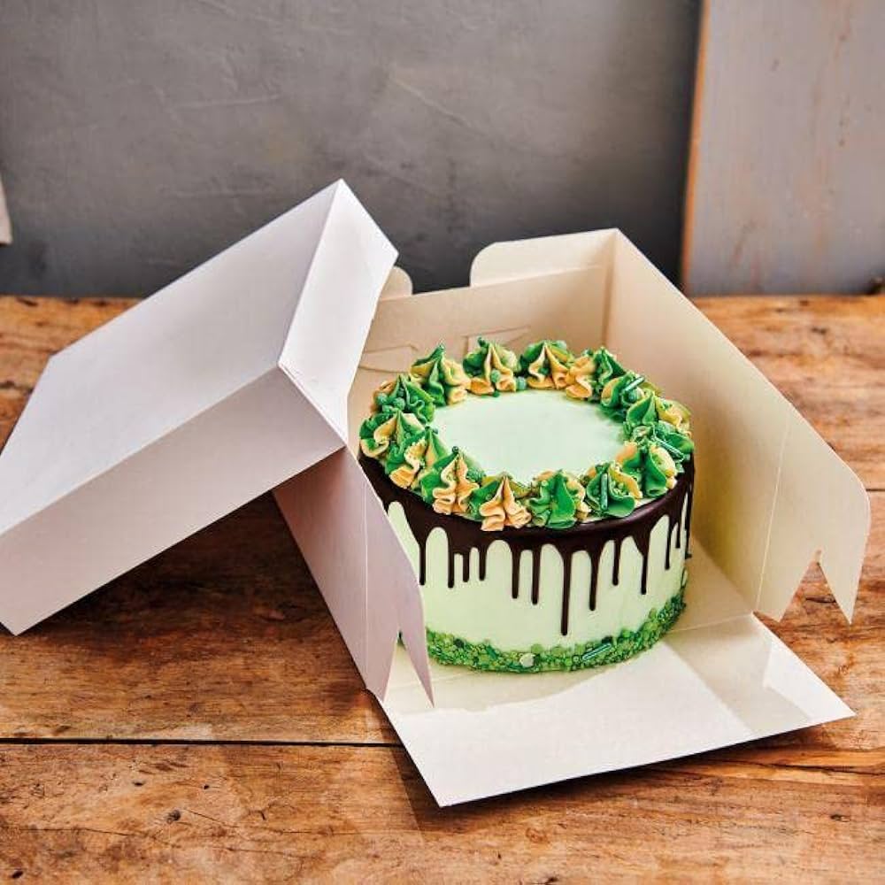 Grön tårta med chokladdrips, som visas upp i en vit tårtkartong med måtten 25 x 25 x 15 cm