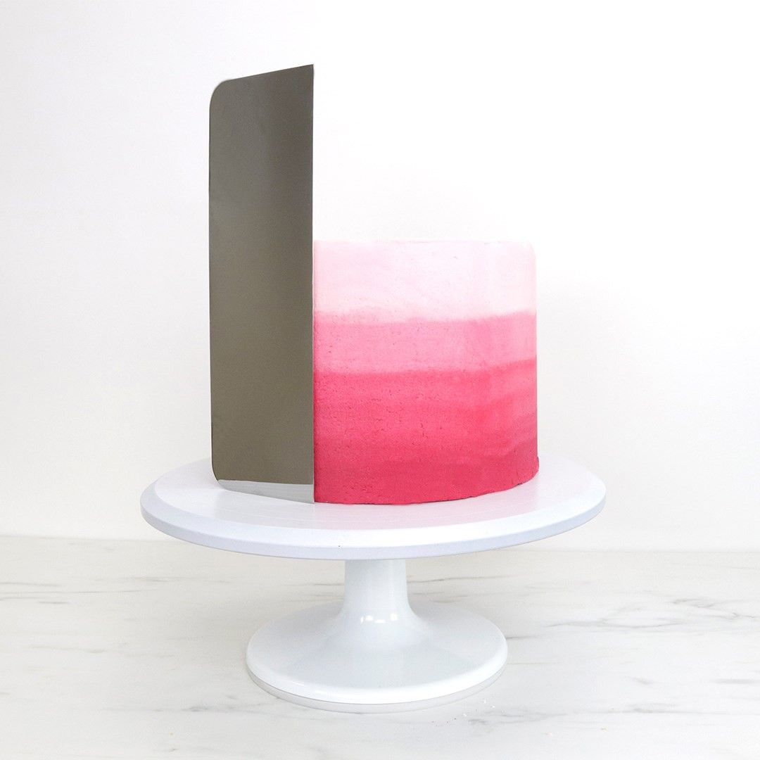 Hög tårtskrapa bredvid en tårta som står på ett vitt tårtfat
