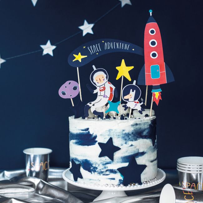 Tårta dekorerad med rymd cake toppers i form av astronaut, raket och stjärnor på mörkblå rymddukning