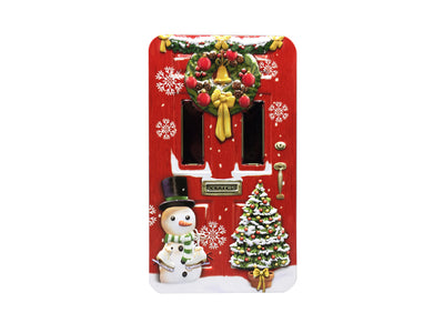 Plåtburk med jultema. Plåtburken är i form av en dörr med en snögubbe, julgran och julkrans