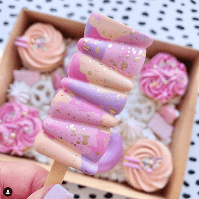 Chokladhjärtan på pinne dekorerade med rosa strössel på ett vitt fat.