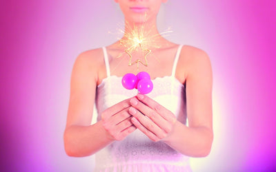 Person håller ett brinnande guldstjärna-tomtebloss i ljus rosa miljö.